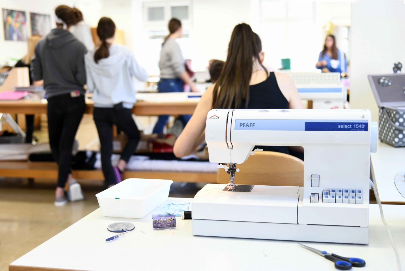Schülerinnen bei der Nähpraxis - im Vordergrund eine Nähmaschine