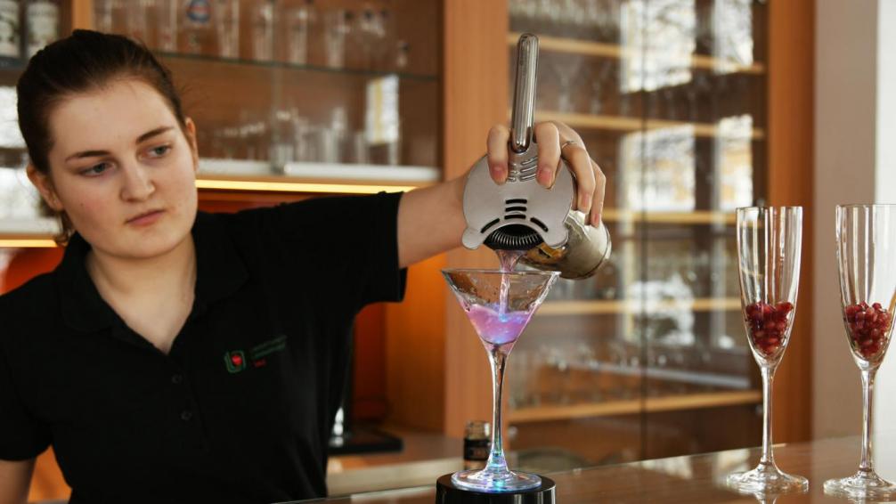 Mädchen schenkt Cocktail ein