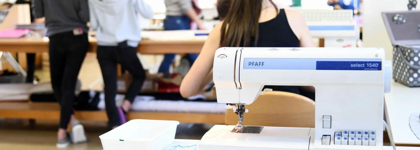 Schülerinnen bei der Nähpraxis - im Vordergrund eine Nähmaschine