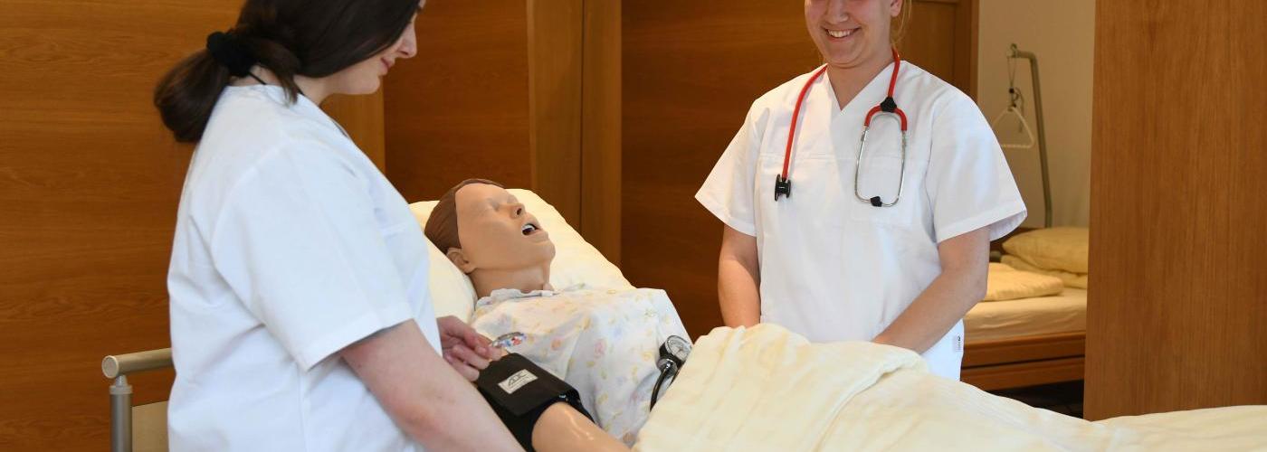 Schülerinnen bei der Pflegeausbildung - Patientenpuppe liegt im Bett